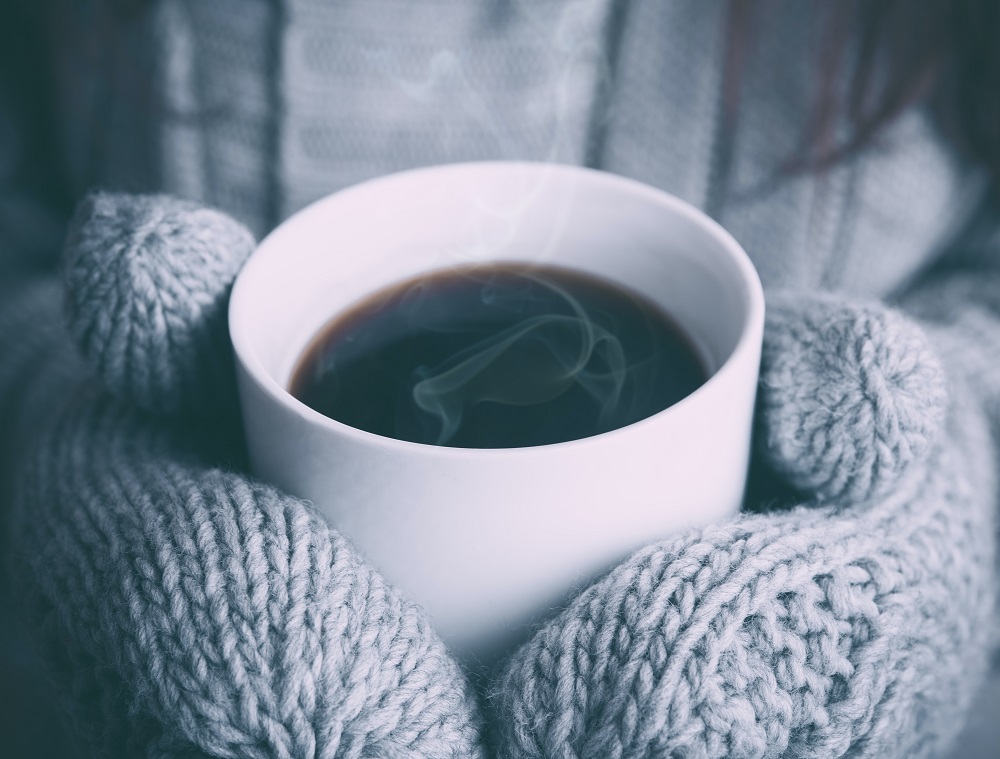 Gloved hands holding a hot cup of coffee on a cold day